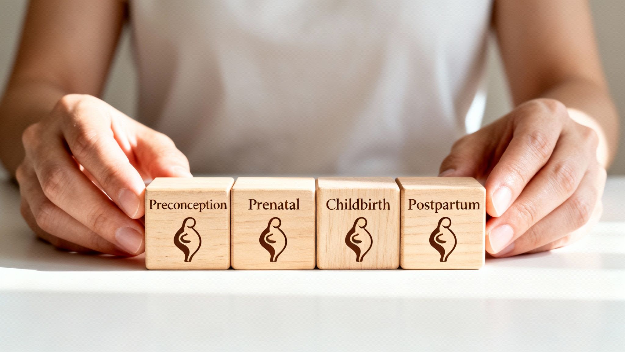 Close-up of hands arranging four wooden blocks depicting the stages of maternity: preconception, prenatal, childbirth, and postpartum.