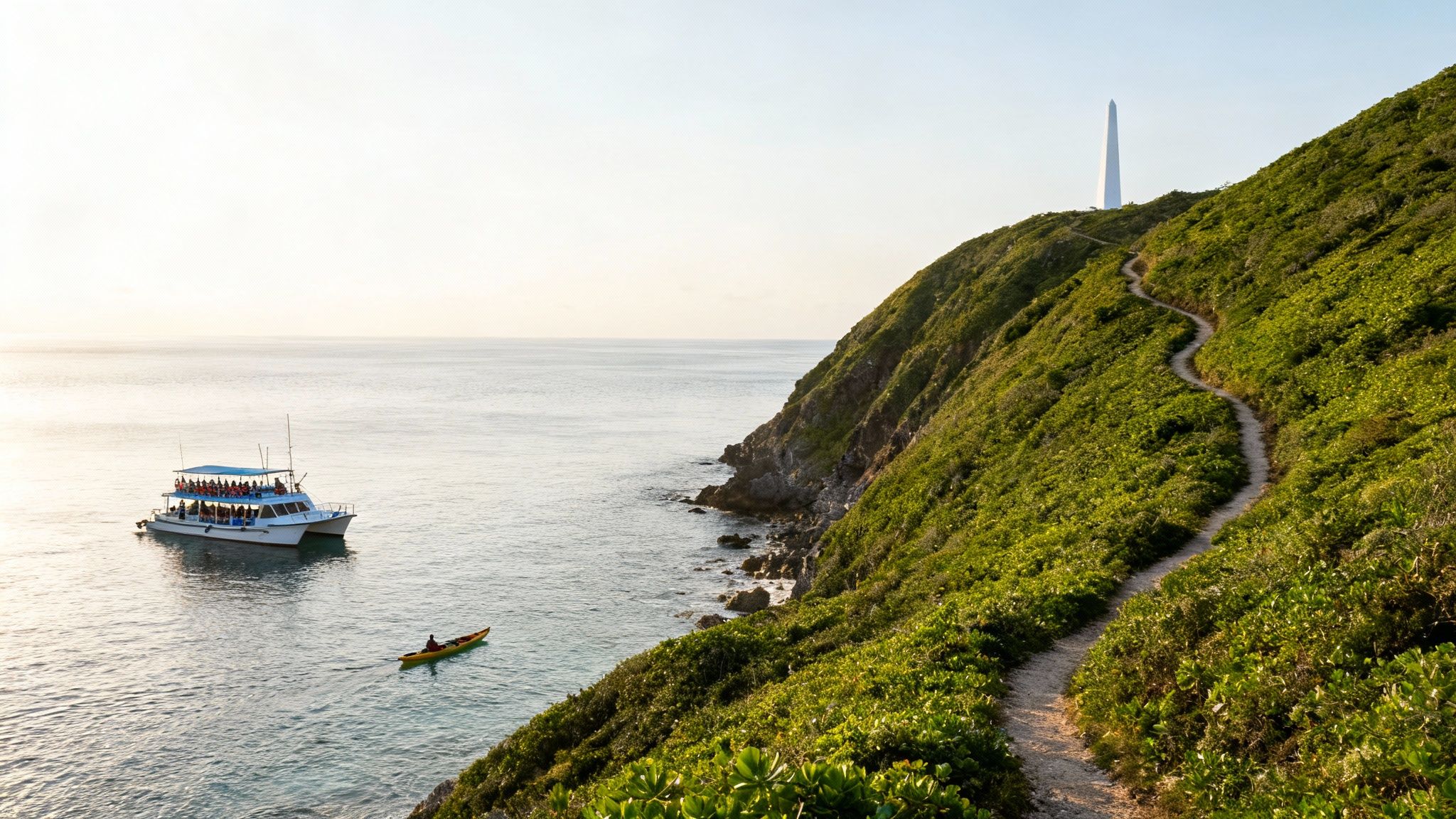 A scenic coastal view with a catamaran, kayaker, winding path on a green hill, and a white monument.