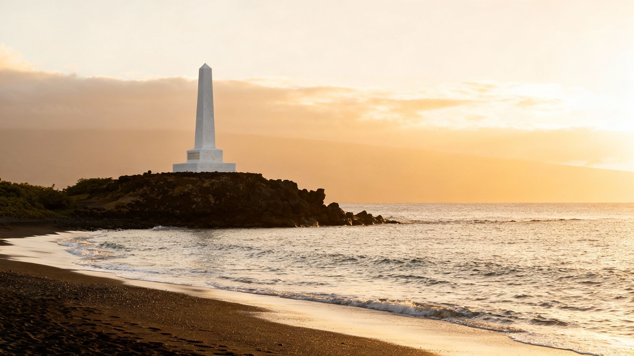 The Captain Cook Monument standing at the edge of the water in Kealakekua Bay.