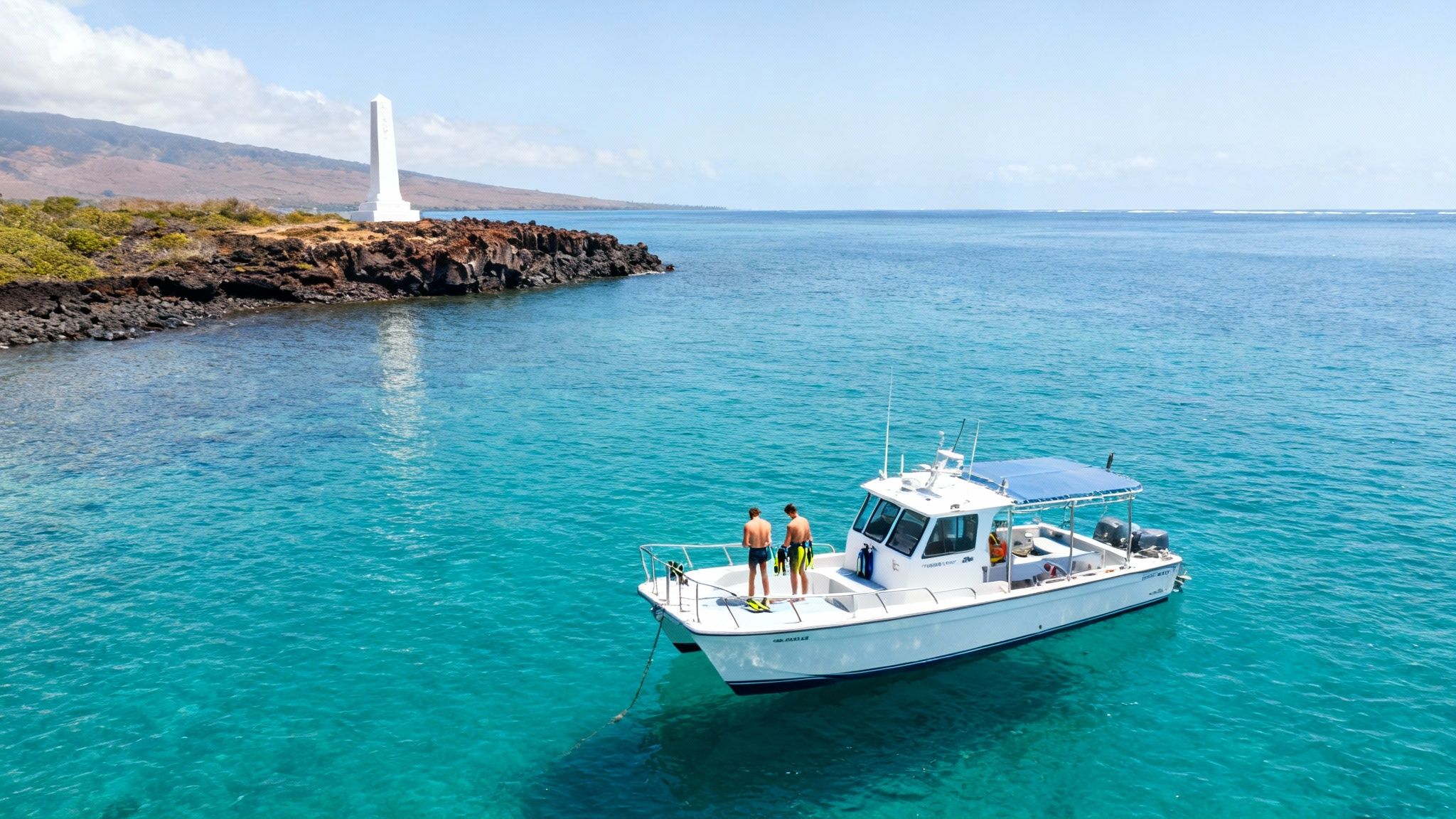 Aerial view of a boat with snorkelers in clear turquoise water, near a rocky coastline and a white monument.