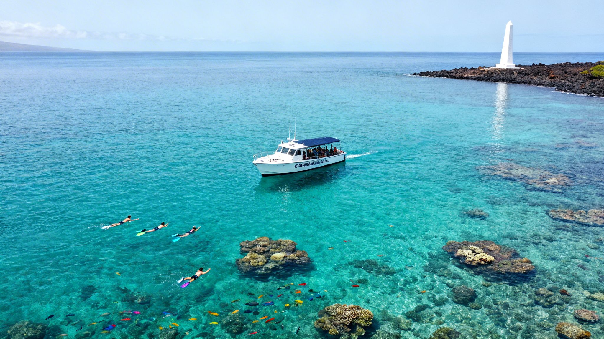 Aerial view of a boat, snorkelers, and colorful coral reefs in clear blue Hawaiian waters.