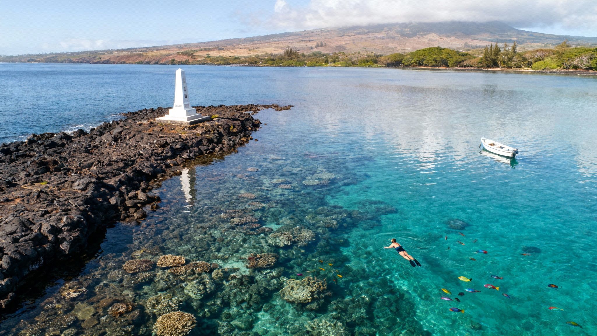 Snorkeler explores vibrant coral reefs and colorful fish near a monument in clear Hawaiian bay.