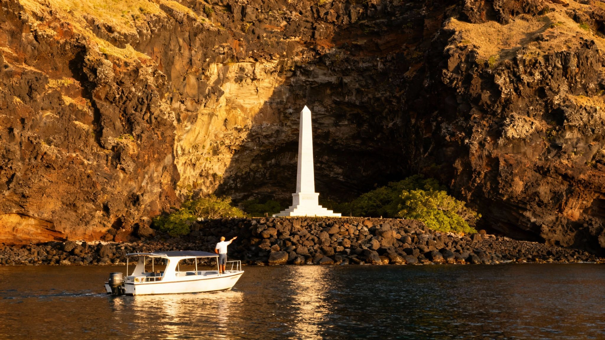 A boat with a person pointing at a white obelisk monument on a rocky shore under a large cliff.