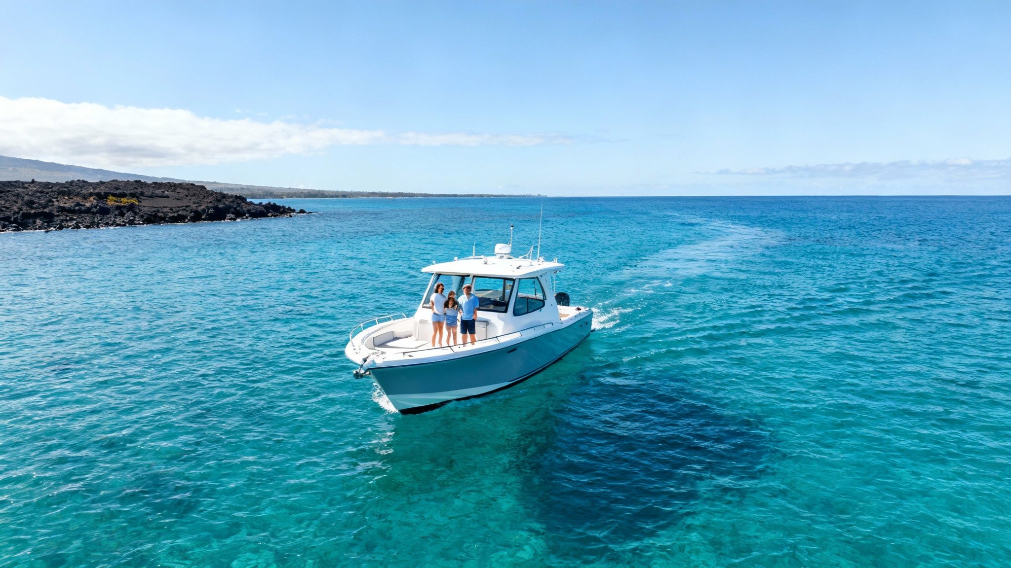 Aerial view of a family on a power boat in turquoise Hawaiian waters with a black lava shoreline.