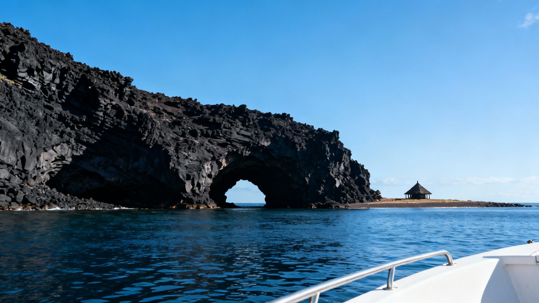 A boat cruises along the rugged, volcanic Kona coastline with lush greenery and dramatic cliffs.