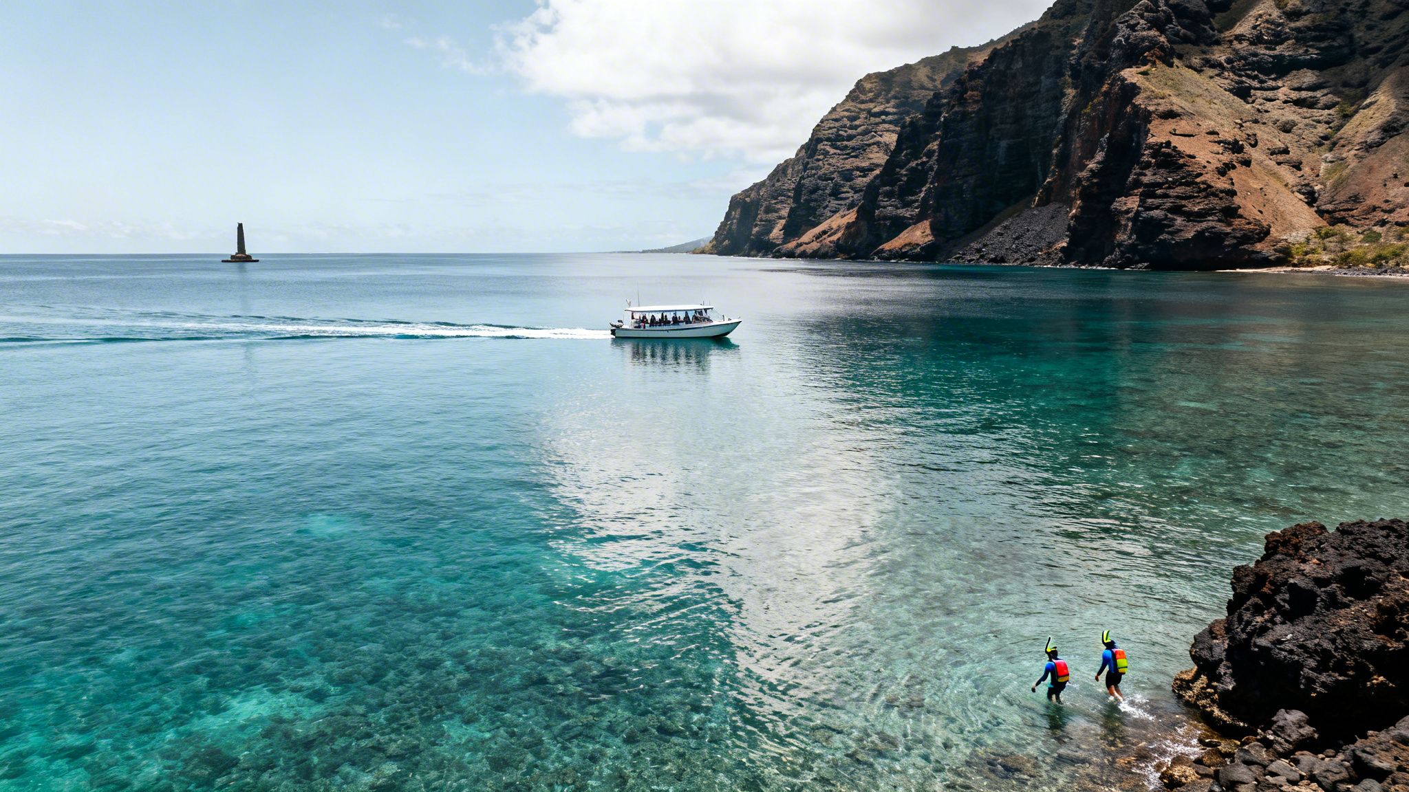 Snorkelers enter clear turquoise water in a scenic bay with a tour boat and distant sea stack.