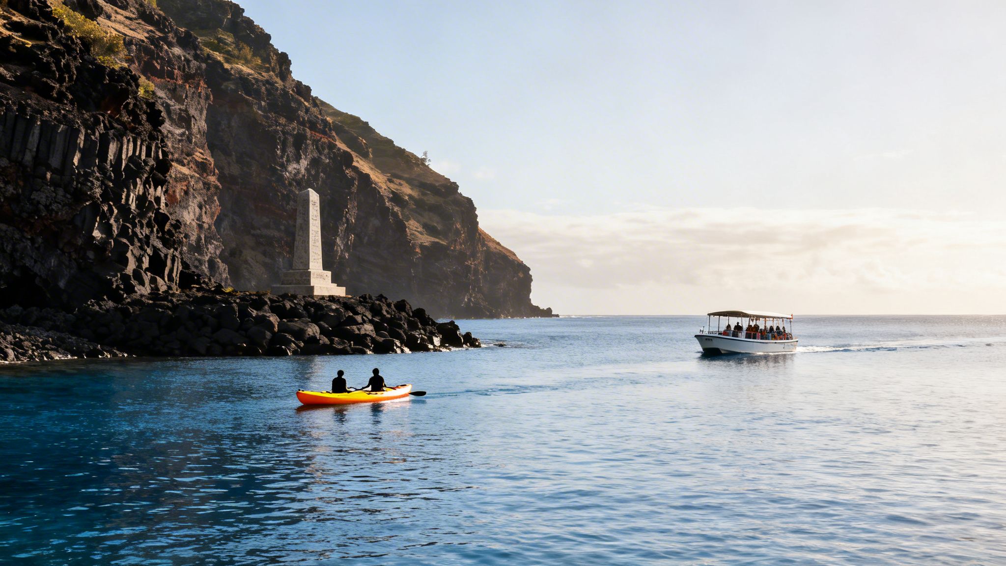 Two people in a yellow kayak paddle near a large cliff and monument while a tour boat passes by.