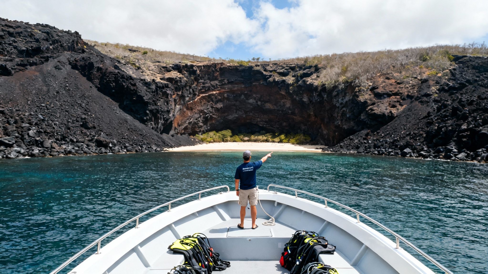 Man on a boat points to a volcanic sea cave with a hidden beach.