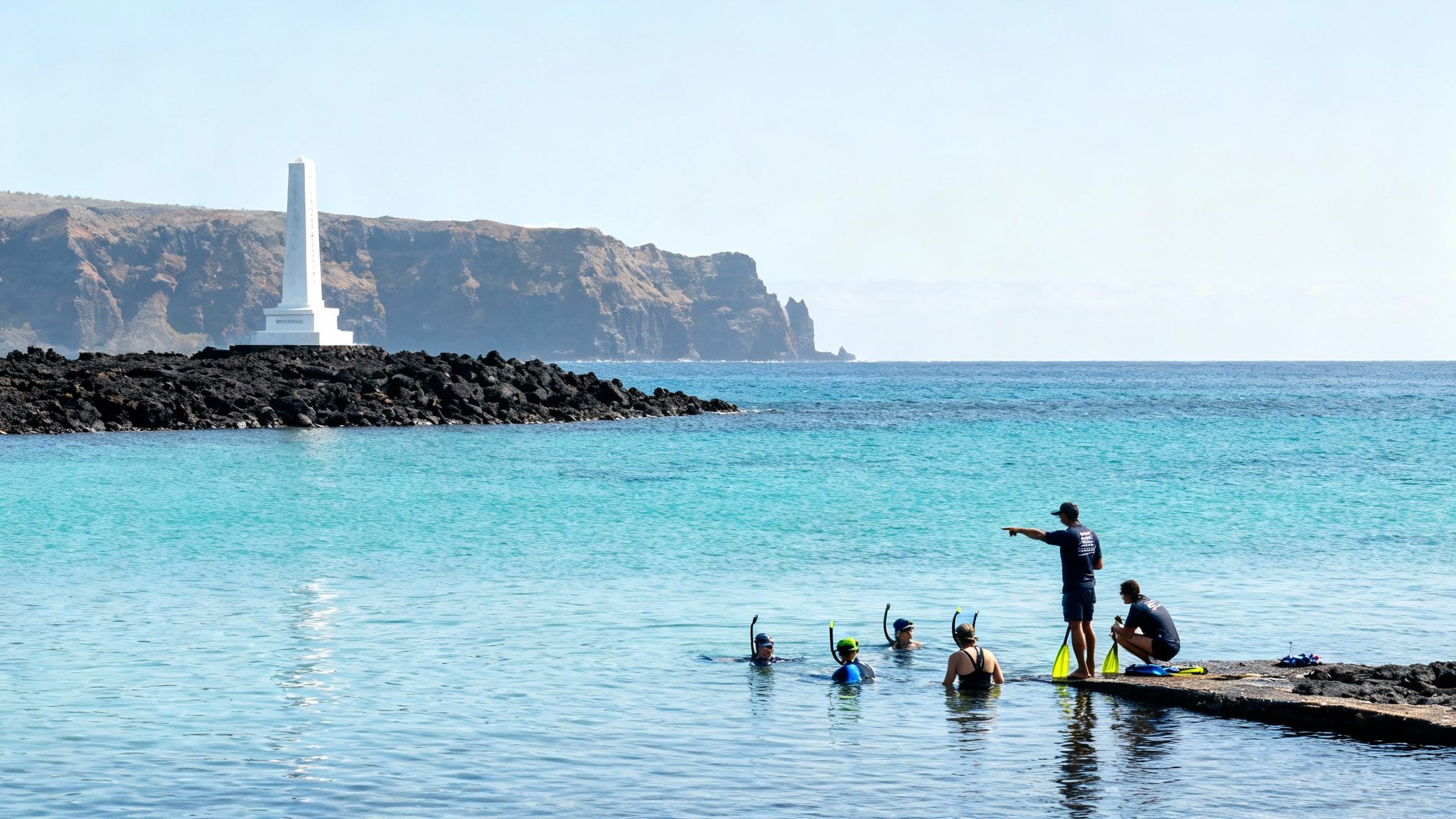 A group of people snorkeling in crystal clear blue water near a white monument on a rocky shore.