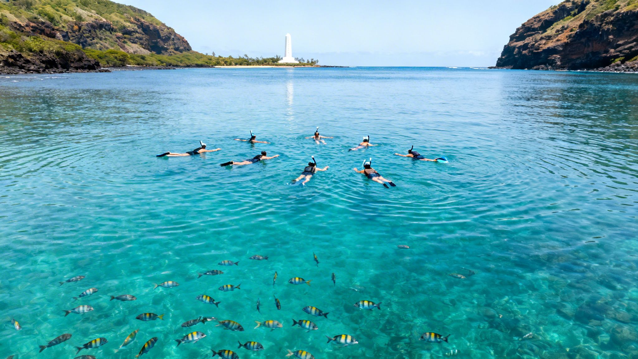 A group of people snorkeling in crystal-clear blue ocean water, surrounded by colorful fish and a distant lighthouse.