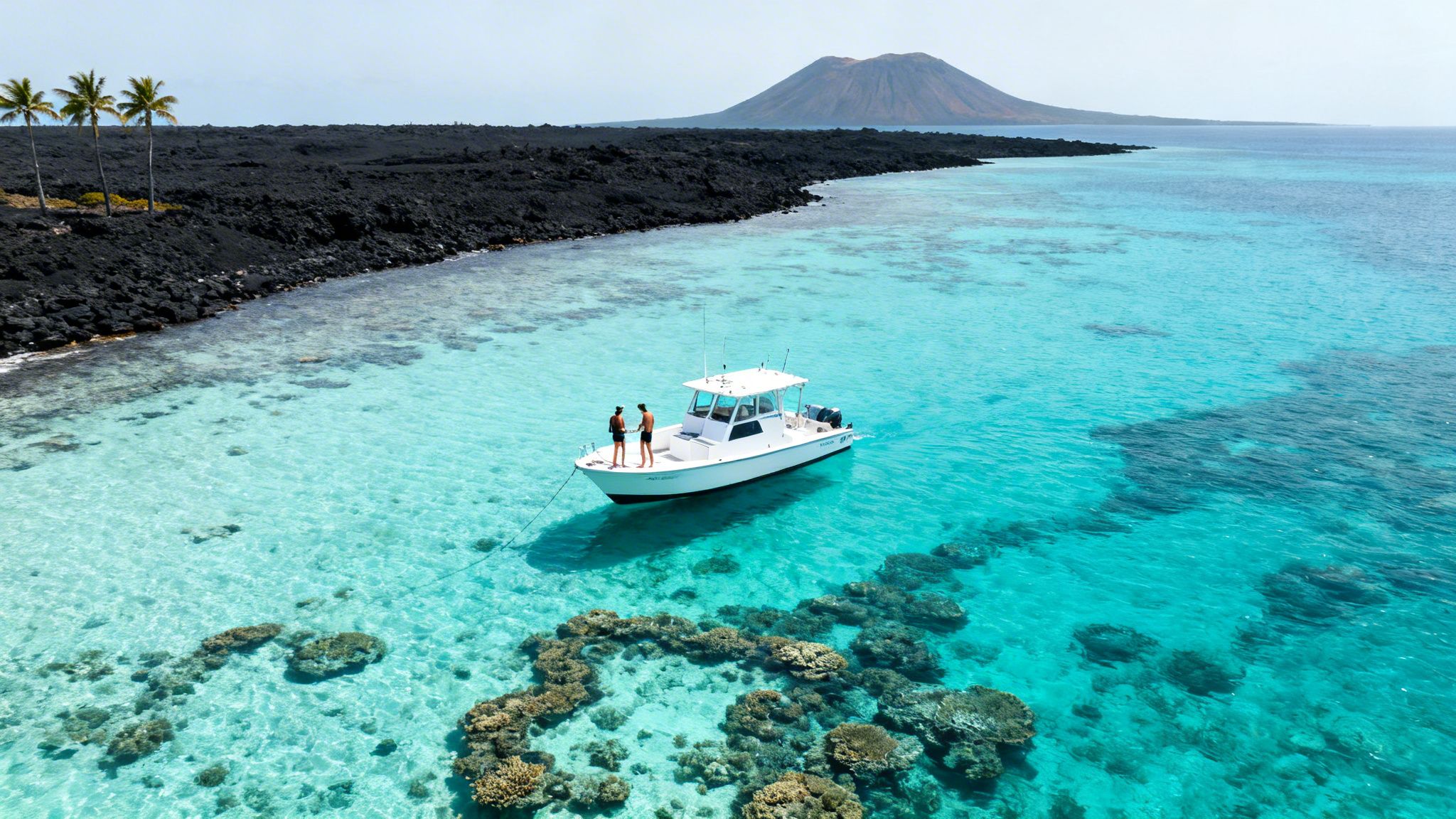Stunning aerial view: boat on clear turquoise water, vibrant coral, volcanic island backdrop.
