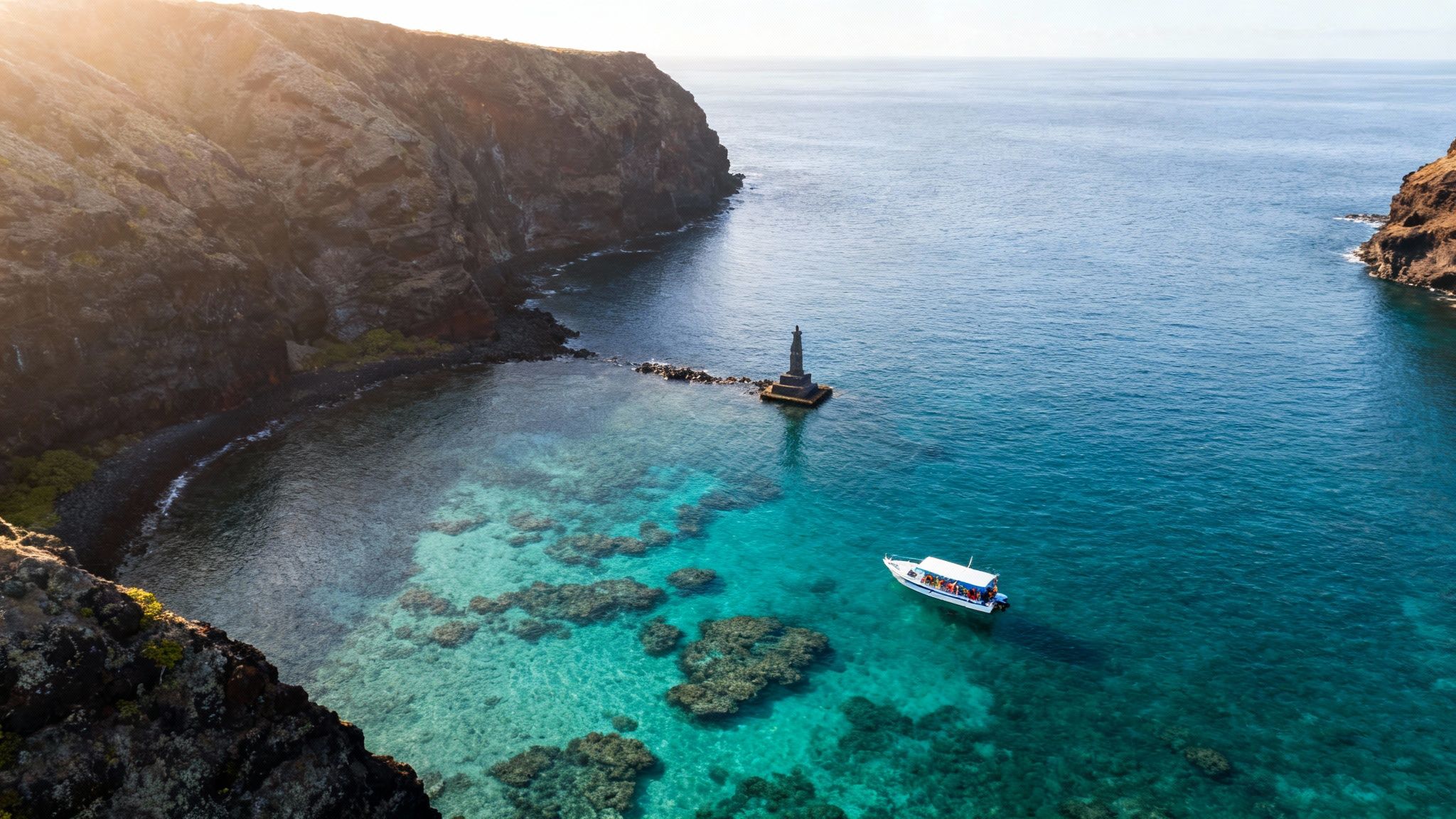 Aerial view of a boat in clear turquoise water near rocky cliffs and a historic monument.