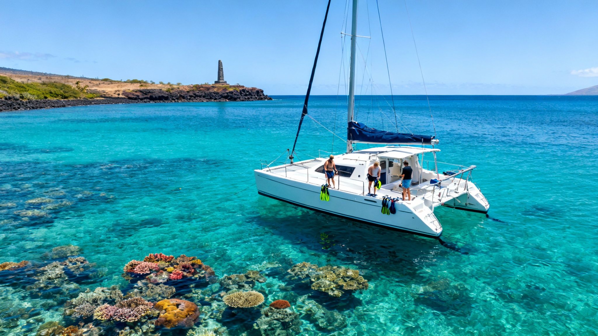 A catamaran boat with people ready to snorkel over colorful coral reefs near Captain Cook monument.