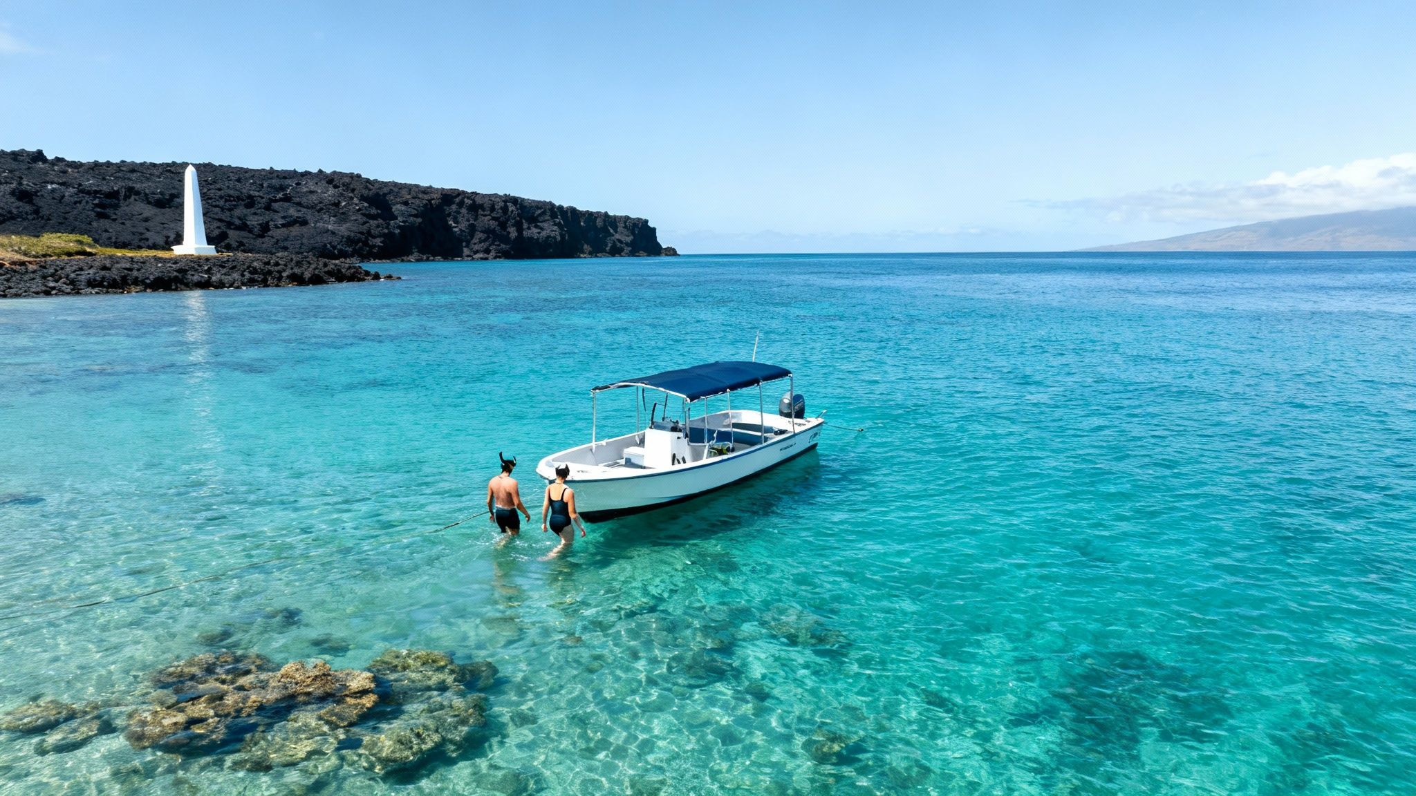 Couple snorkeling near a boat in clear tropical water with a rocky coastline and monument.
