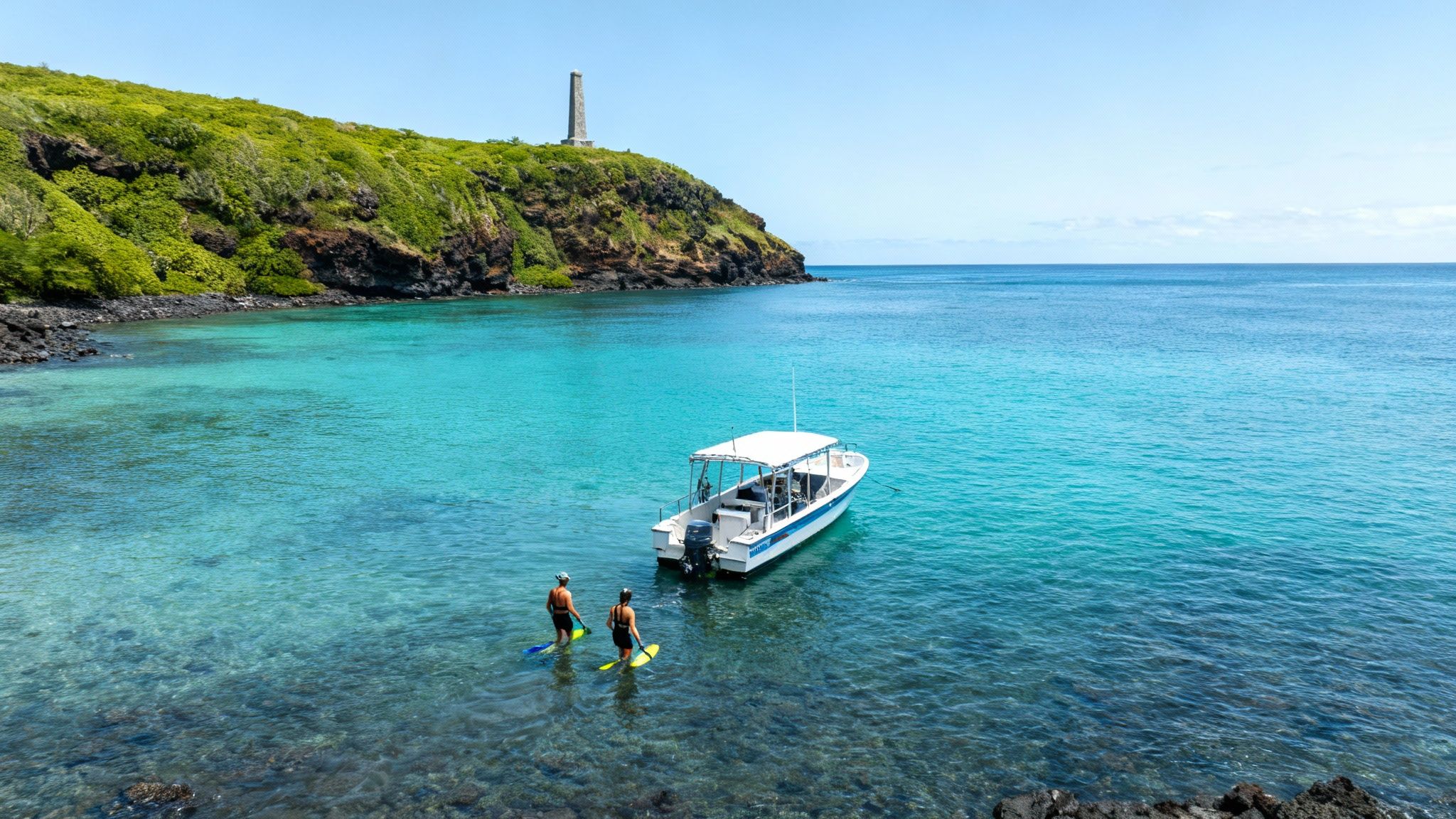 Two snorkelers with fins in clear turquoise water near a boat and a lush green cliff with a monument.