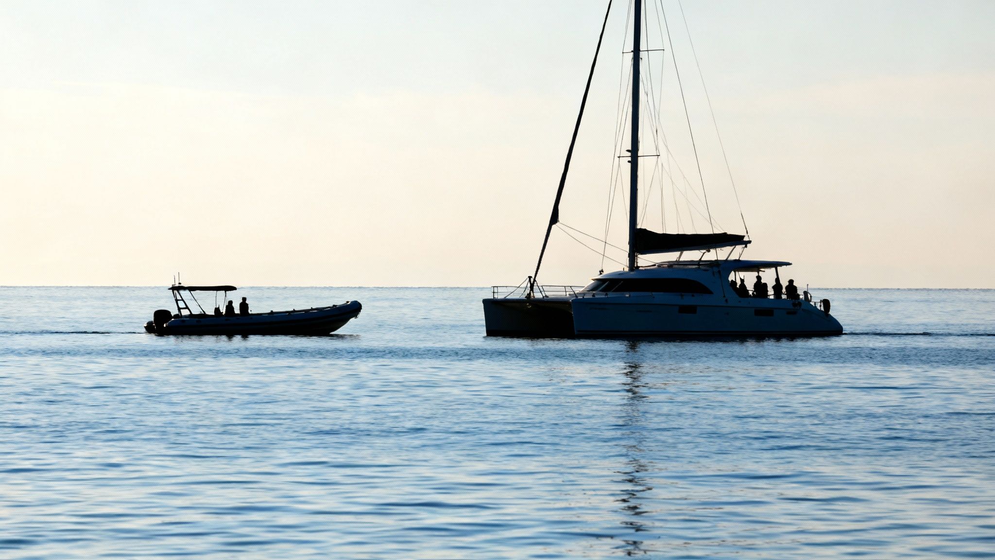 Two different types of tour boats, a large catamaran and a smaller raft, in Kealakekua Bay.