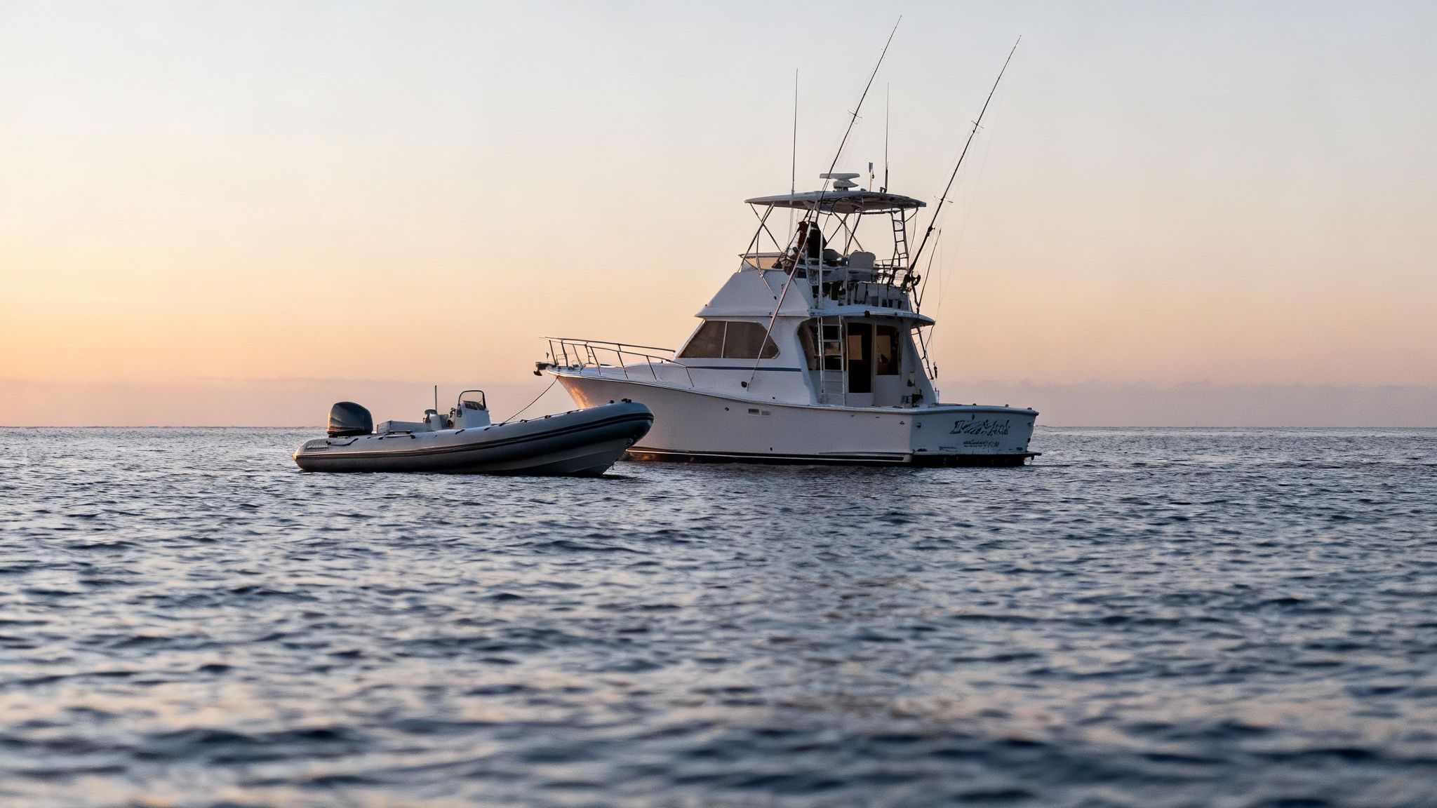 Snorkelers floating on the surface at night, holding onto a light board, as a large manta ray swims just below them.