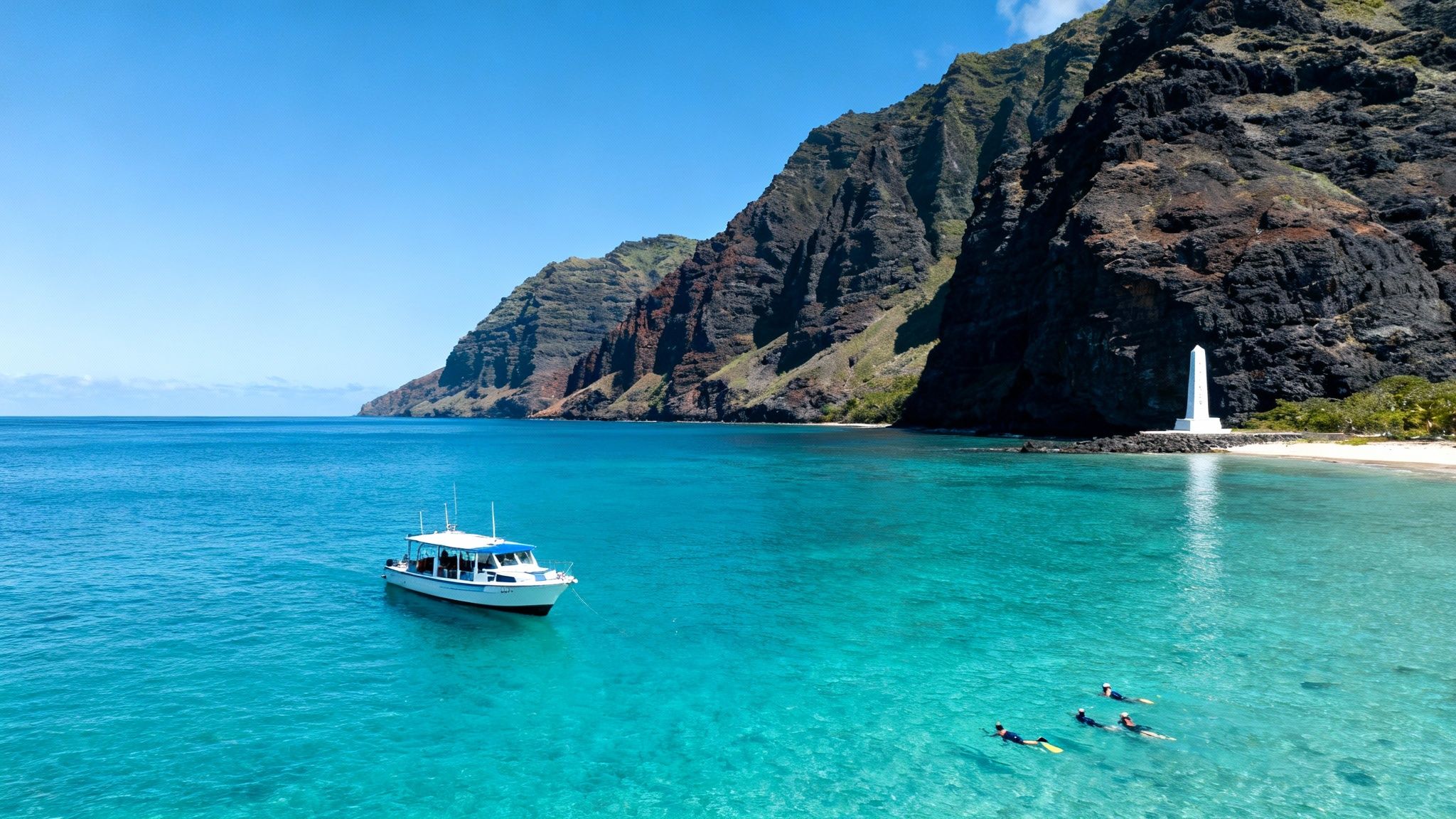 A boat and snorkelers in clear blue Hawaiian waters, with a dramatic cliff coast and a white monument.