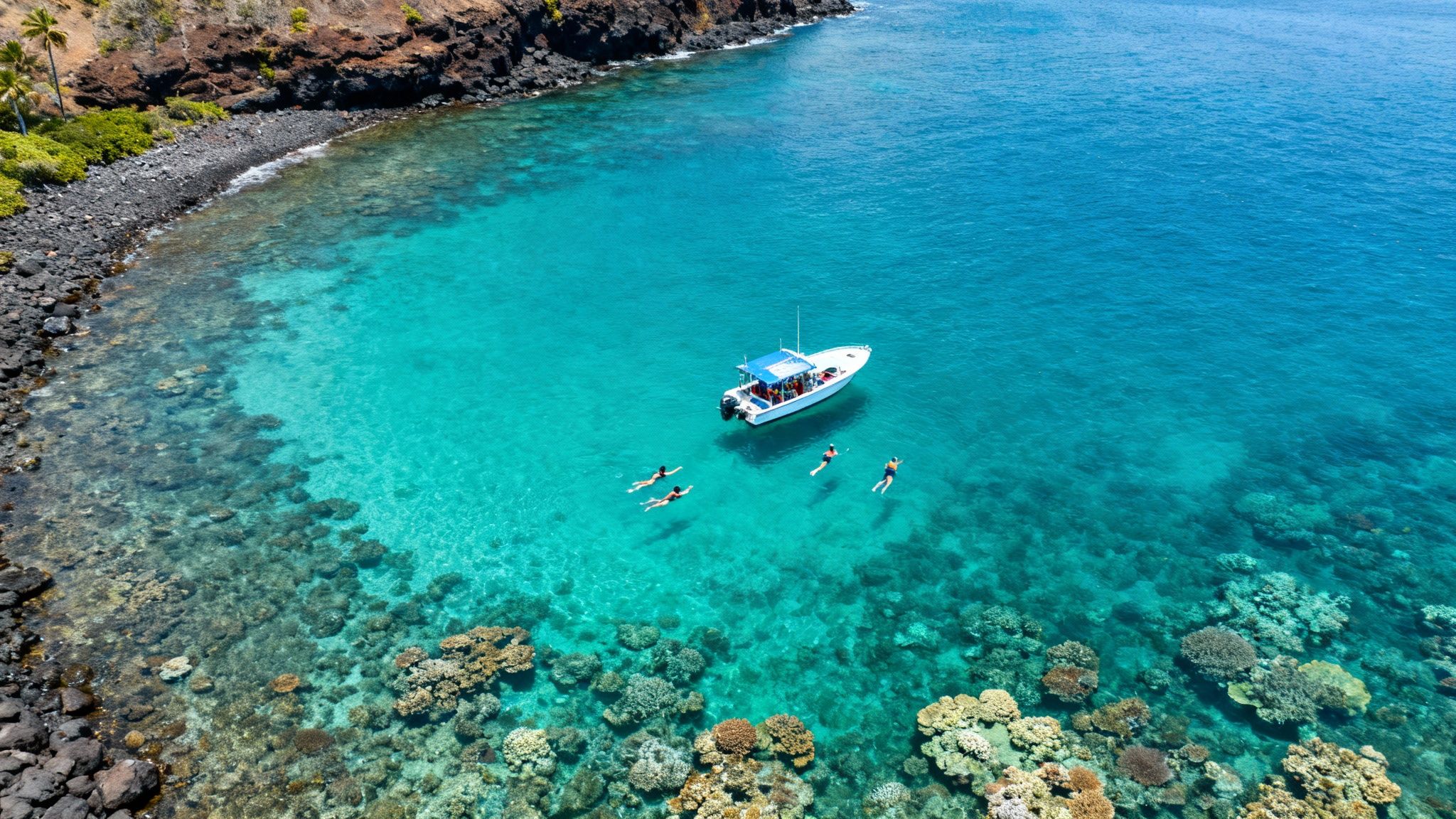 Aerial view of a boat and snorkelers exploring vibrant coral reefs in clear turquoise water.