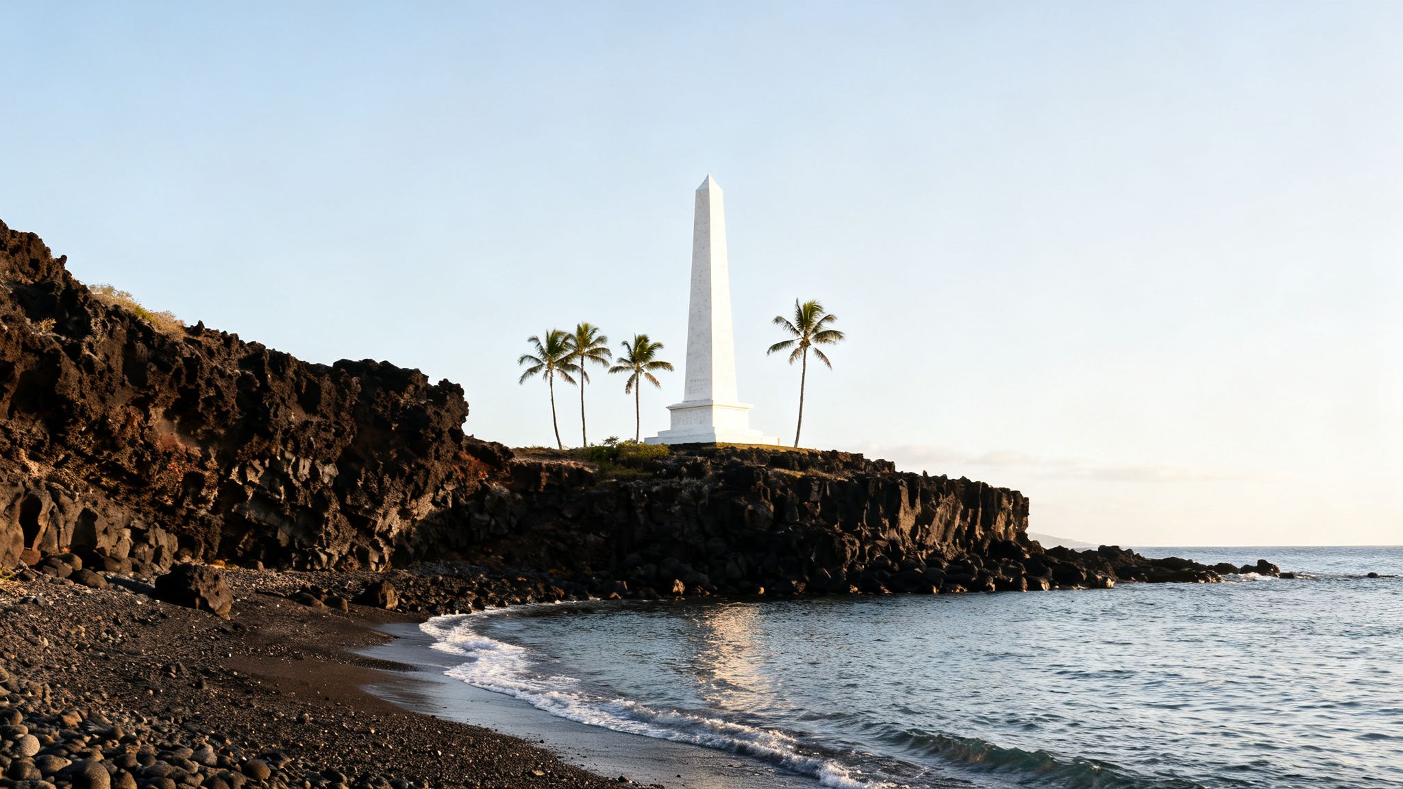 A tall white obelisk monument stands on a dark rocky cliff overlooking a black sand beach and ocean.