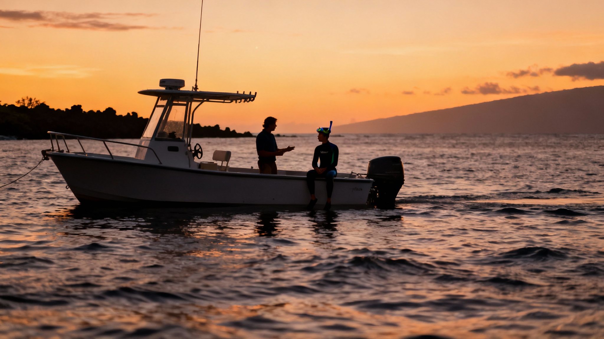 A snorkeler in the dark ocean water watching a massive manta ray swim just beneath them in the glow of a light.