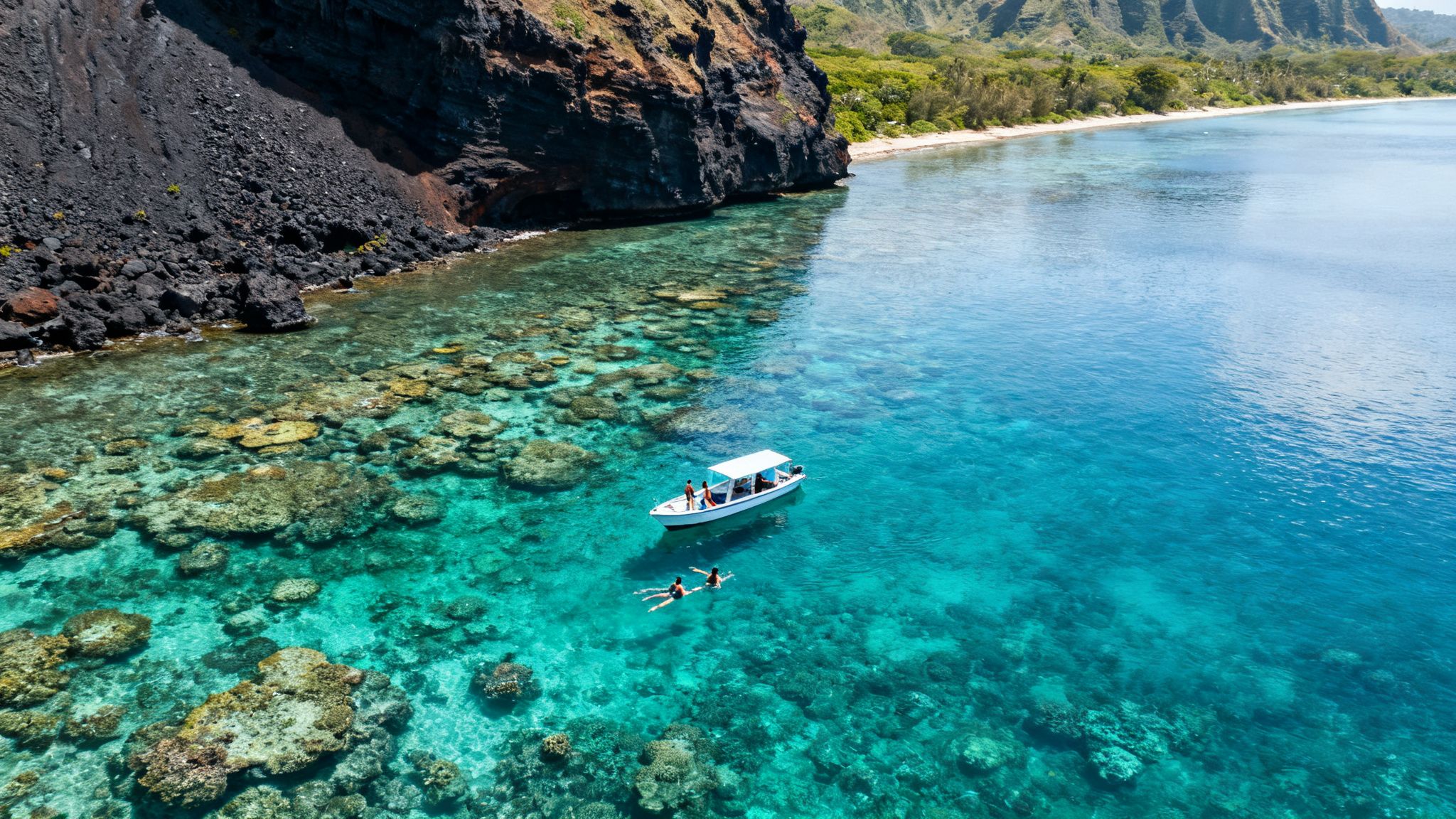 Snorkelers and a boat exploring vibrant coral reefs in Hawaii's clear turquoise waters.