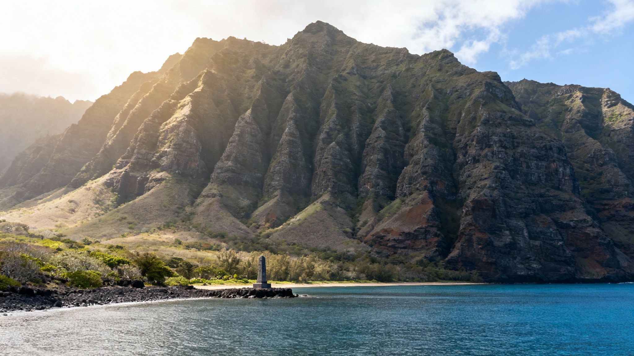 A view of the Captain Cook Monument across Kealakekua Bay with lush green cliffs in the background