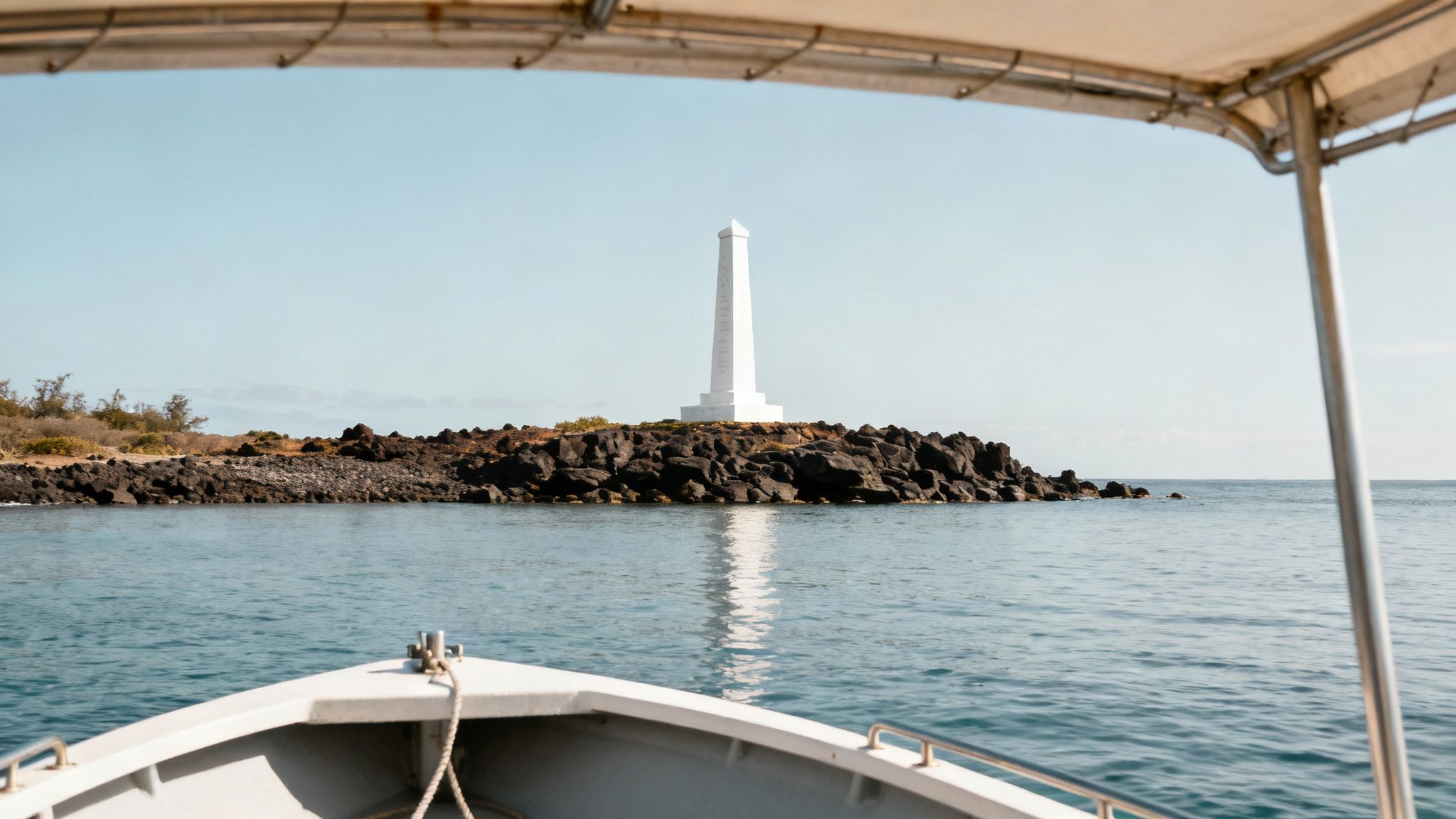 A view of the Captain Cook Monument from the water, with the green cliffs of Kealakekua Bay in the background.