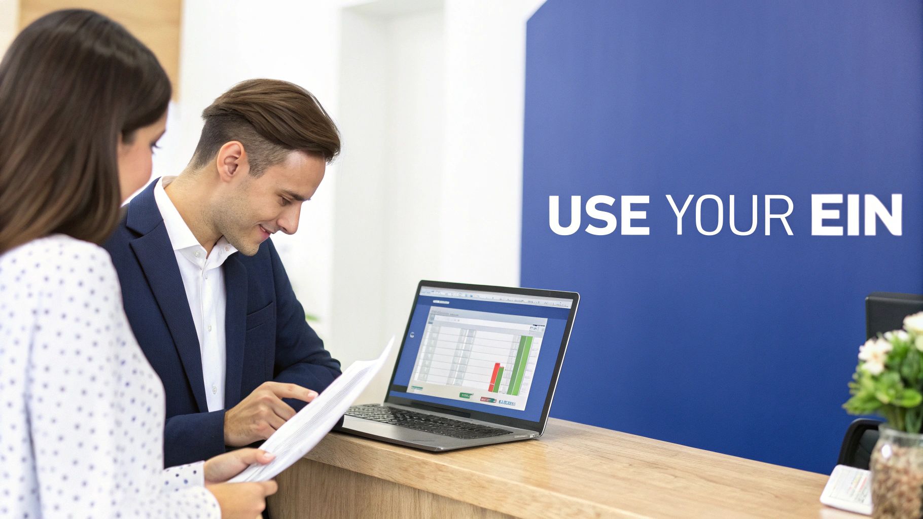 Two business professionals reviewing documents and financial data on a laptop in an office with 'USE YOUR EIN' text.