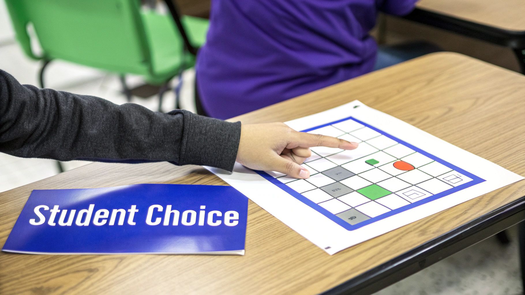 Close-up of a student's hand pointing at a grid-based learning activity, with a 'Student Choice' booklet.
