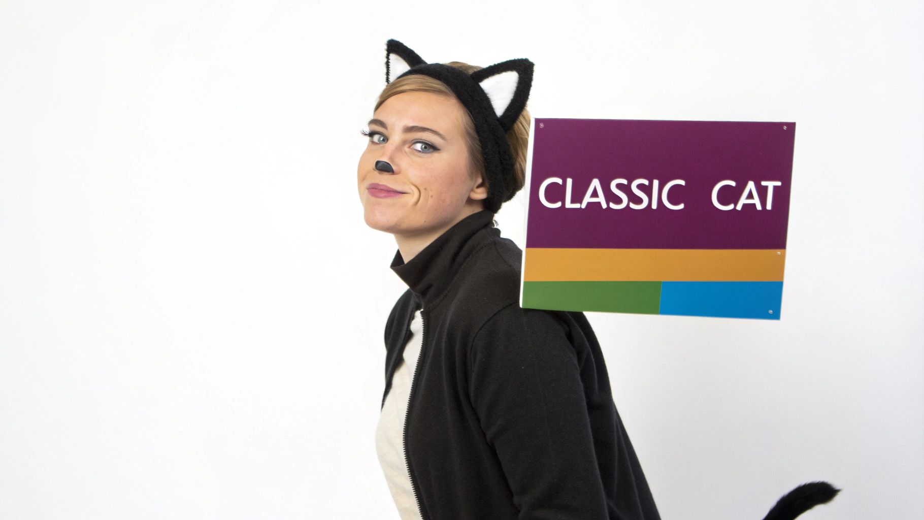 A smiling woman in a black cat costume with ears and painted nose, holding a 'CLASSIC CAT' sign.
