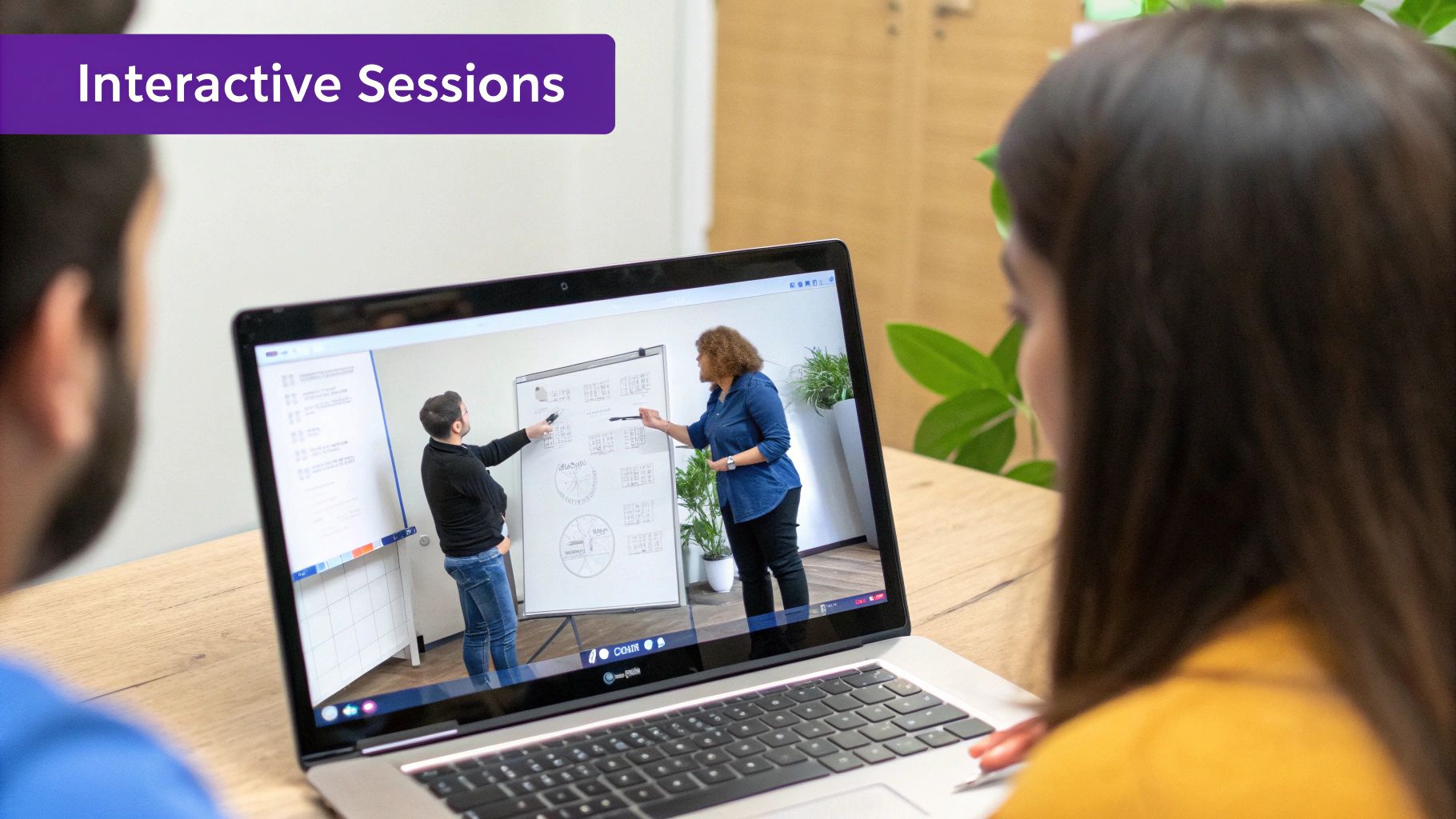Two people watch an interactive online session on a laptop, showing presenters explaining concepts on a whiteboard.