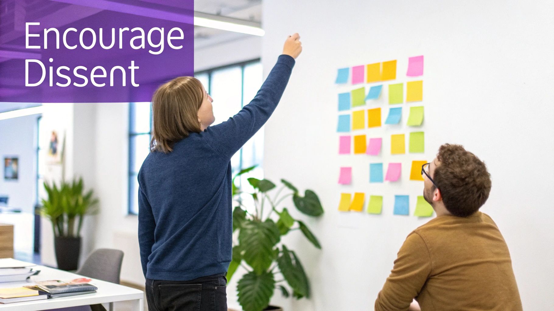 Two colleagues brainstorm, placing colorful sticky notes on a wall, embodying the message 'Encourage Dissent'.