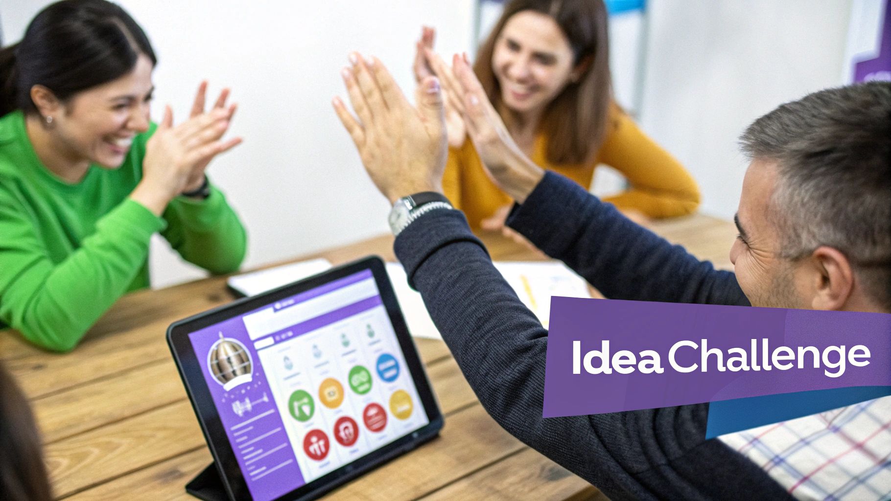 Three smiling colleagues celebrate success with high-fives during an 'Idea Challenge' meeting with a tablet.