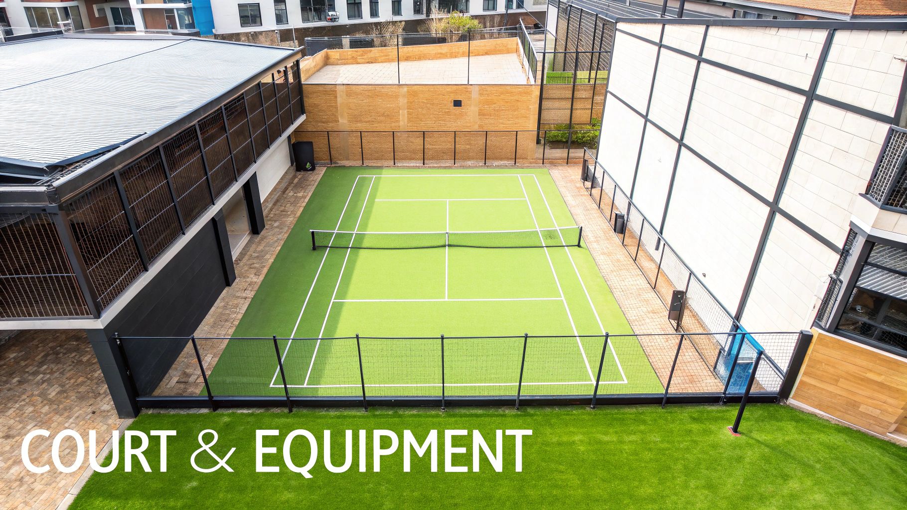 A wide-angle view of an empty blue padel court, showing the glass walls, mesh fencing, and net.
