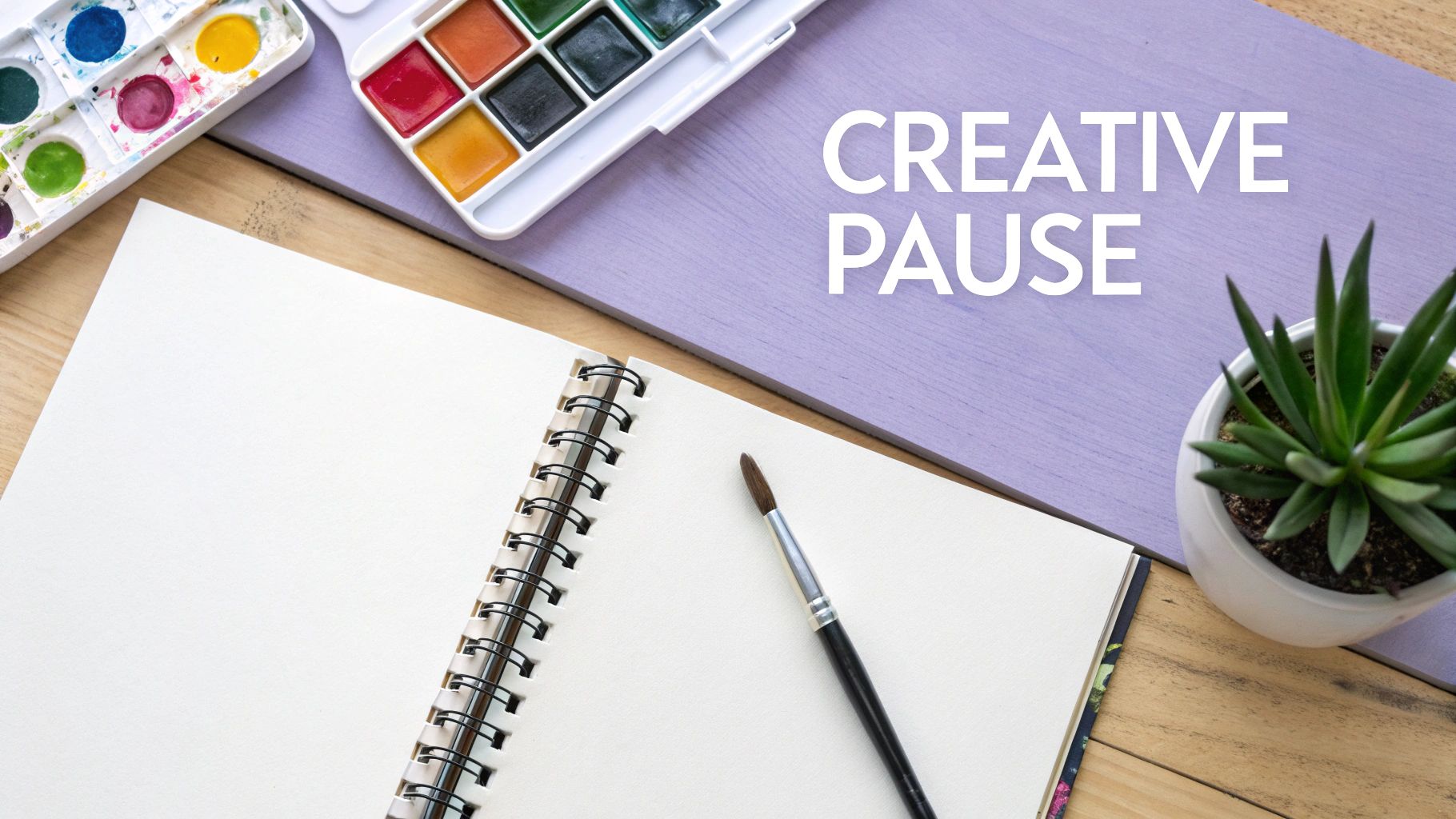 A person's hands sketching a floral design in a notebook with various art supplies like pencils and paintbrushes scattered around.