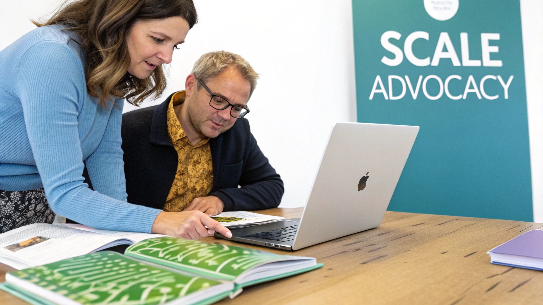 Two professionals review content on a laptop and papers, with a 'SCALE ADVOCACY' banner visible.