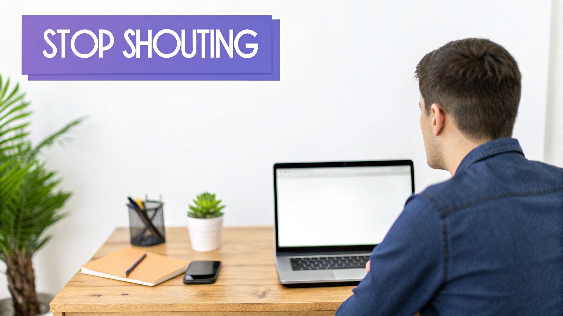 A person at a wooden desk with a laptop, notebook, and plants, with a 'STOP SHOUTING' banner.