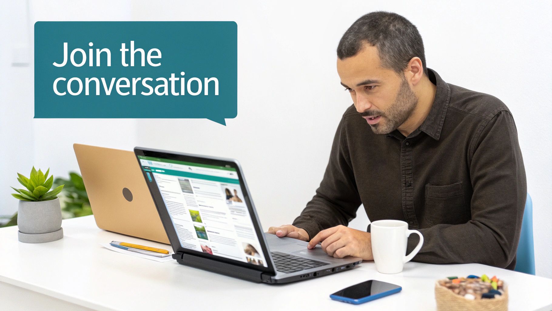 A man works on a laptop at a white desk with a plant and mug, a speech bubble says "Join the conversation."
