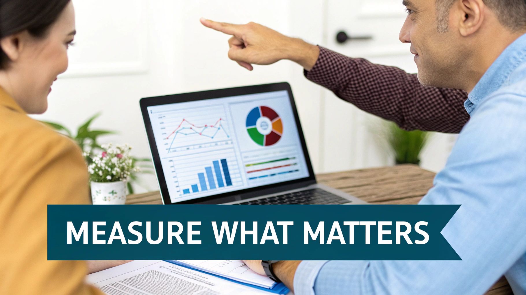 Two smiling business professionals analyze data visualizations on a laptop screen, discussing performance metrics.