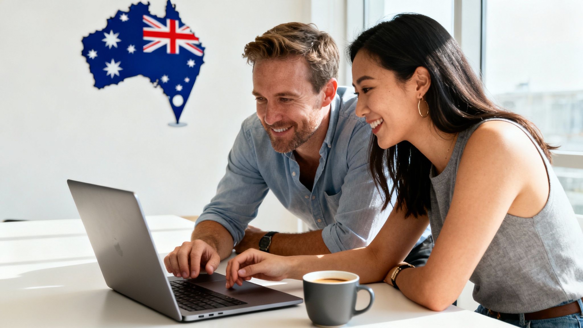 Smiling man and woman looking at a laptop, with an Australia map on the wall.