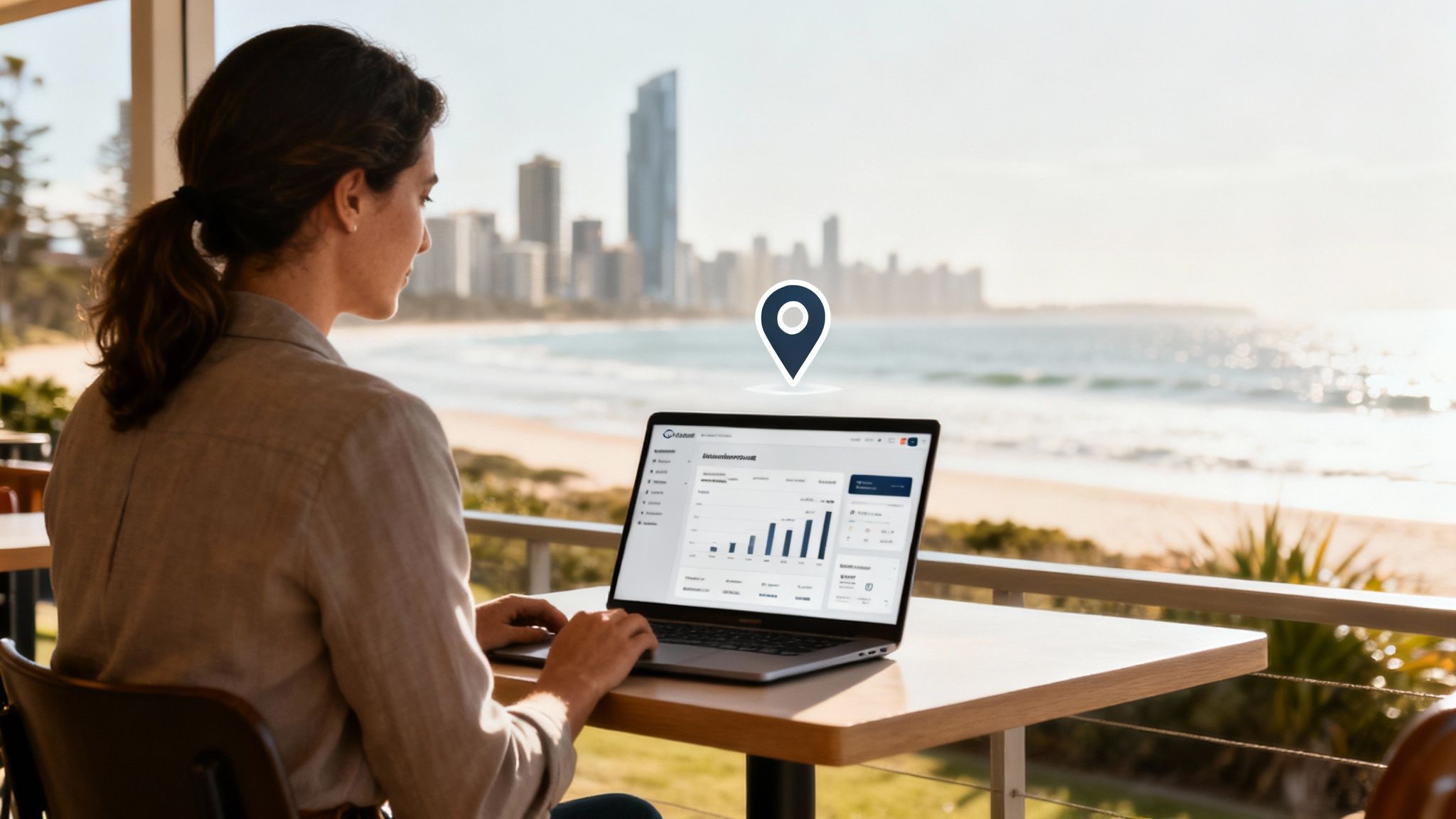 A woman works on her laptop at a table with a stunning Gold Coast beach and city view.