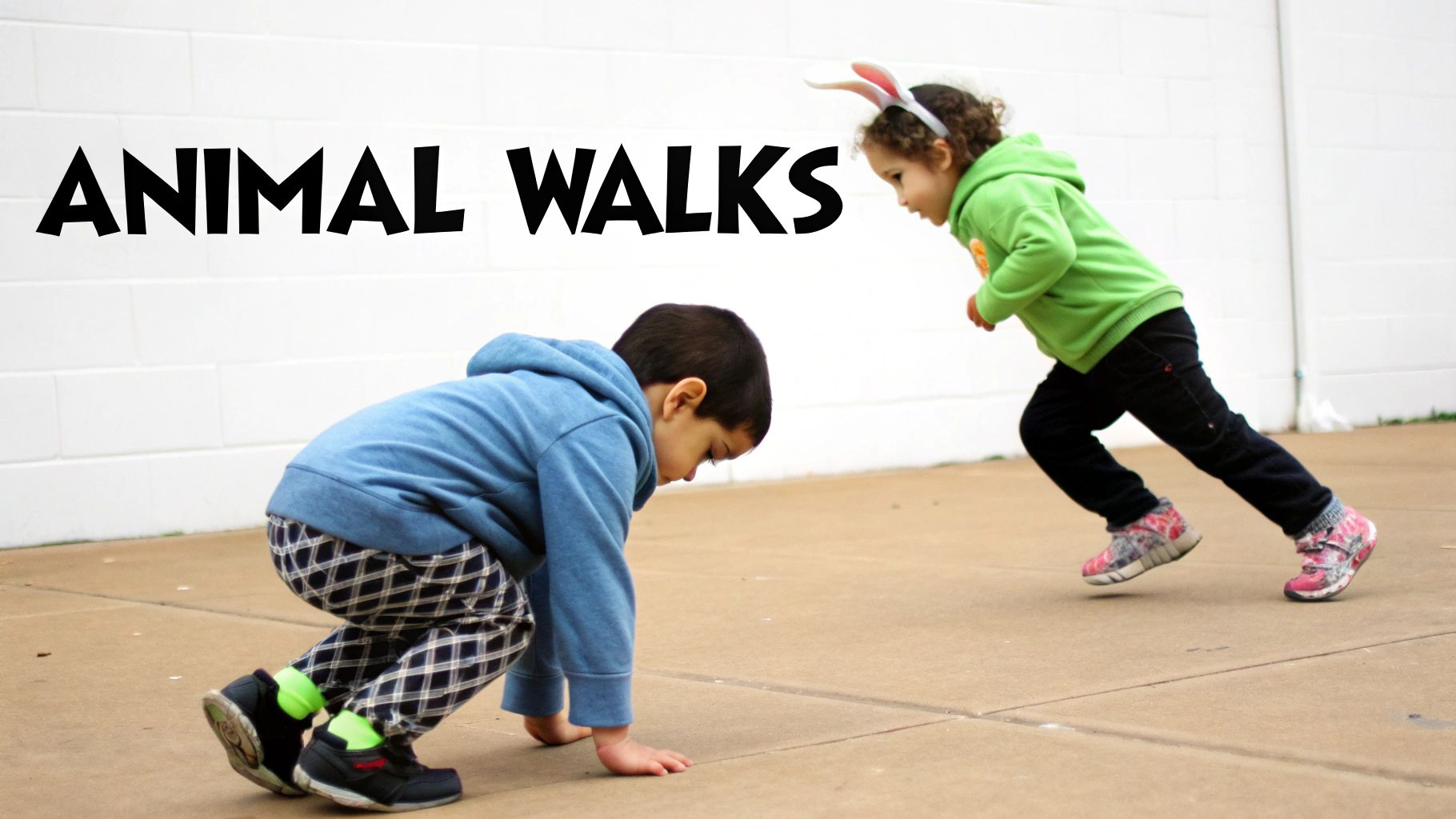 Two children play 'Animal Walks' outside, one crawling and the other running with bunny ears.