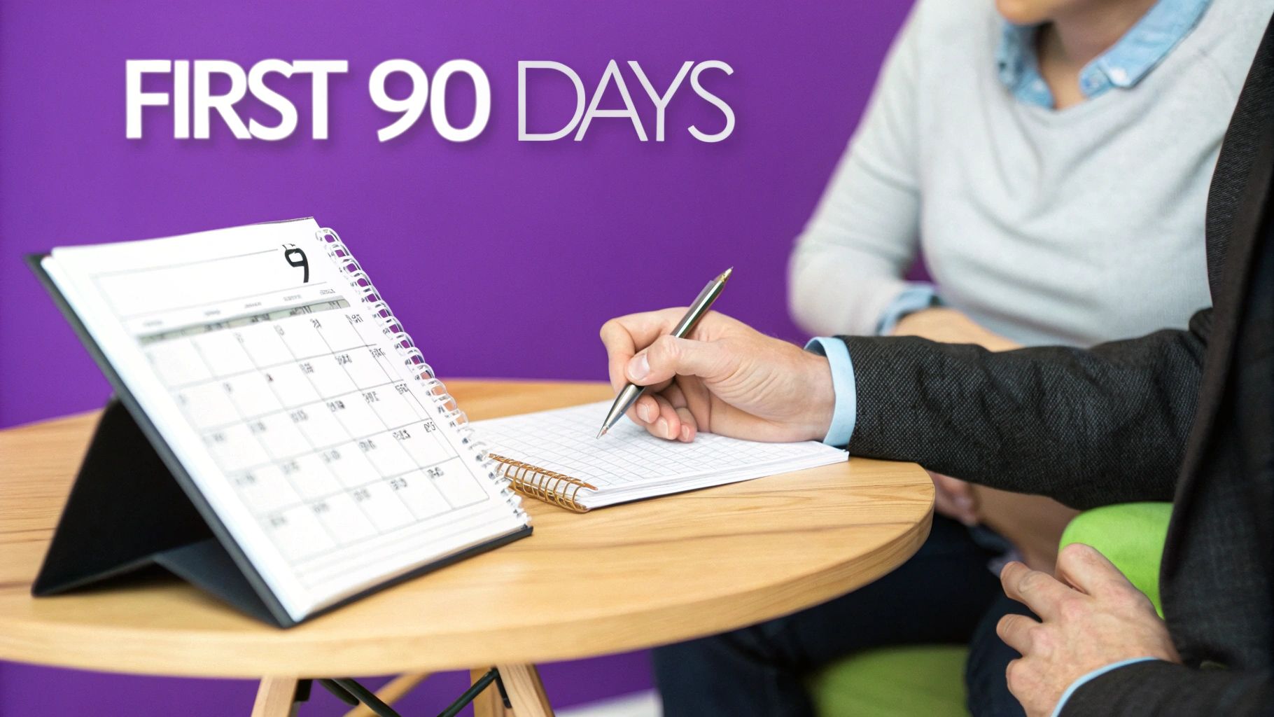A person writes notes in a planner during a business meeting about the first 90 days.