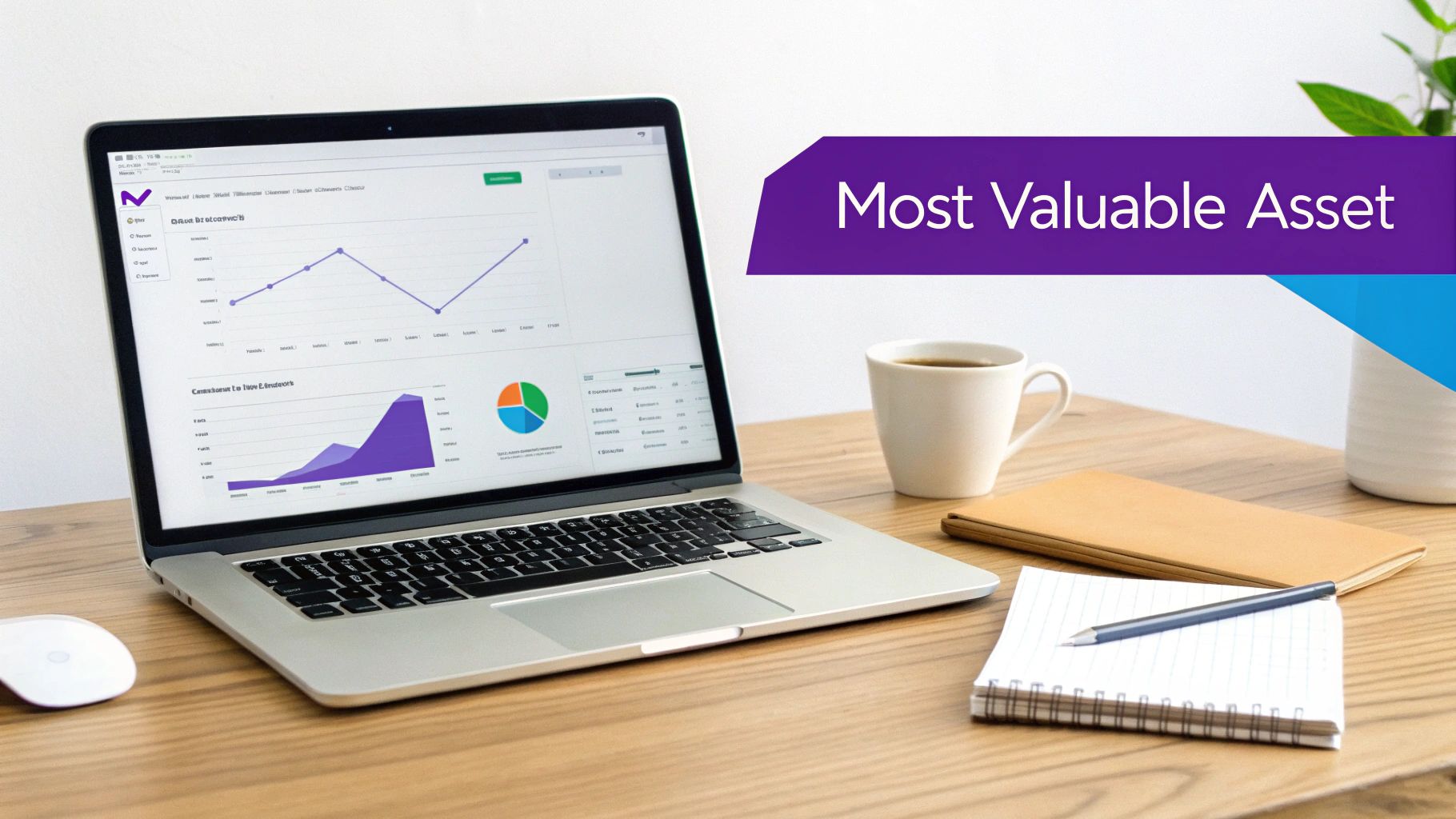 A laptop displaying business analytics is on a wooden desk, with coffee, notebook, and 'Most Valuable Asset' banner.