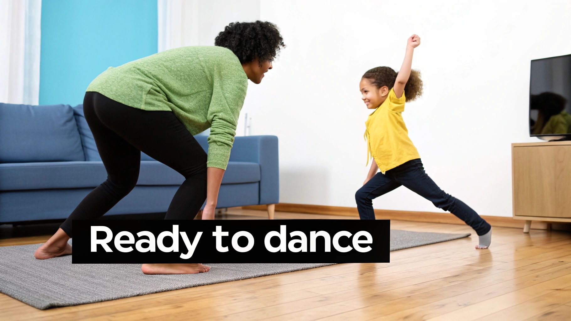 A smiling woman and a young girl in a living room, ready to dance together.