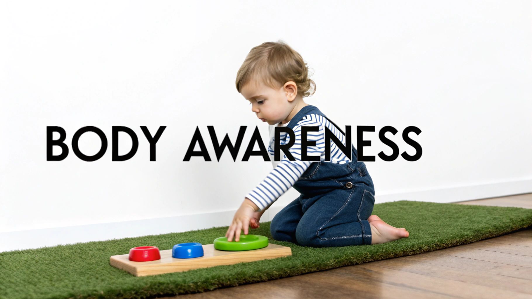 A toddler on a green mat plays with colorful stacking rings, enhancing body awareness.