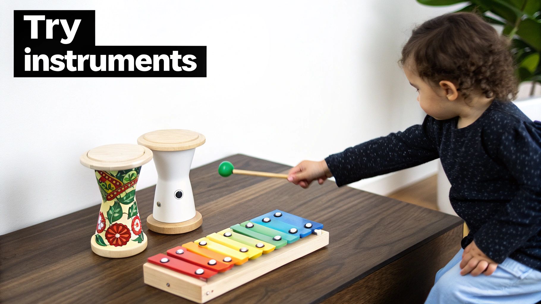 A young child plays a colorful xylophone and drums on a wooden table.