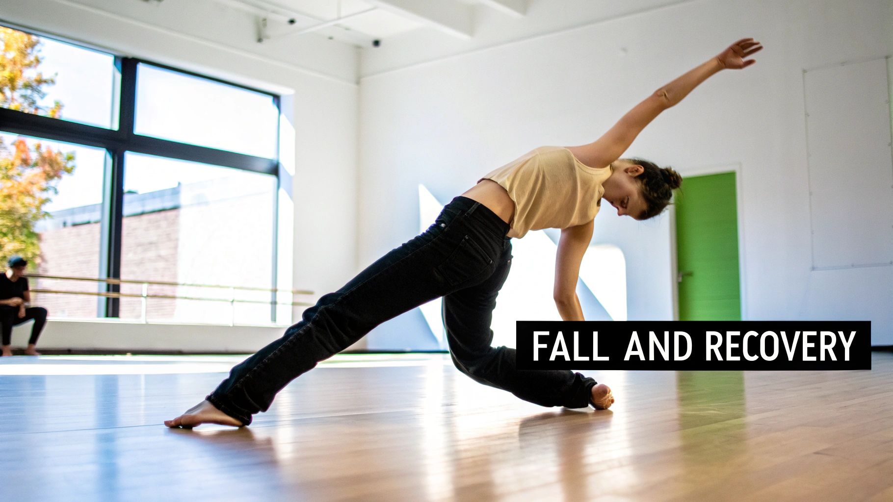 A modern dancer gracefully performs a 'fall and recovery' movement on a wooden studio floor.