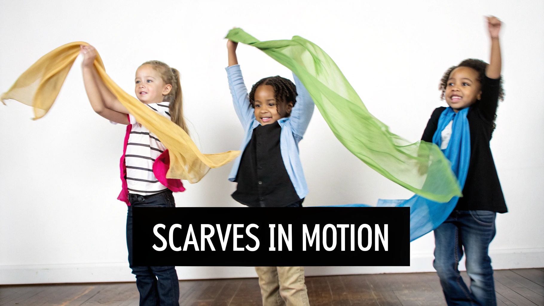 Three joyful young children, two girls and one boy, actively play with vibrant, flowing scarves in a creative movement activity.